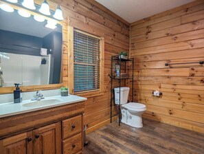 Ein Badezimmer mit Holzwandverkleidung, Waschbecken, Spiegel und Toilette.