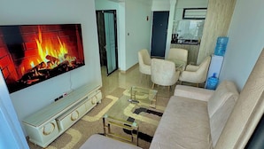 Una sala de estar moderna con televisor de pantalla plana, sofá color beige, mesa de centro de vidrio y chimenea.