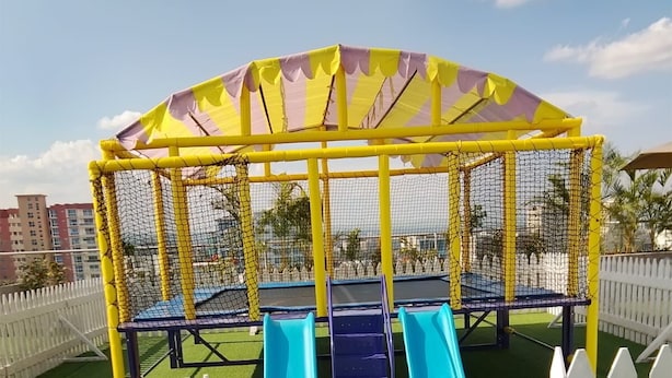 Un parque infantil con dos toboganes y una zona de escalada con red.