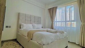 Un dormitorio con una cama grande, un tapete mullido y un ventanal con cortinas.