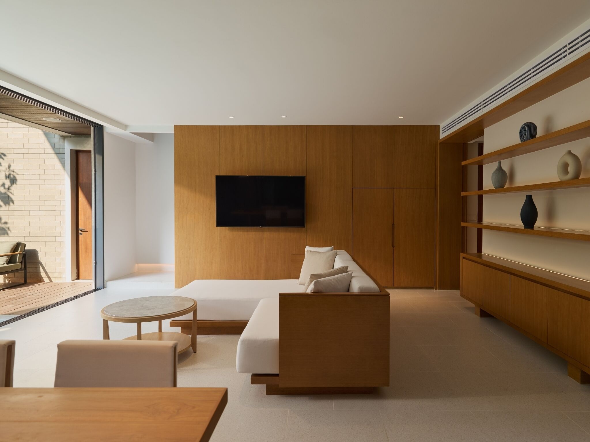 A modern living room with a sofa, a coffee table, and a TV mounted on the wall.