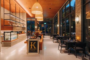 Interior moderno de un restaurante con techo de madera, iluminación colgante y una barra central que muestra el logotipo 'Khaomon'.