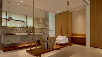 A modern bathroom with a marble sink, wooden swing chairs, and a large mirror.