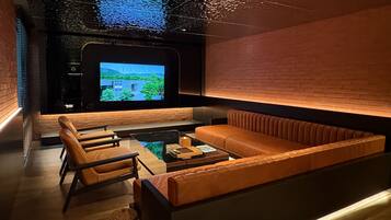 A modern lounge with a large screen, leather seating, and a unique ceiling design.