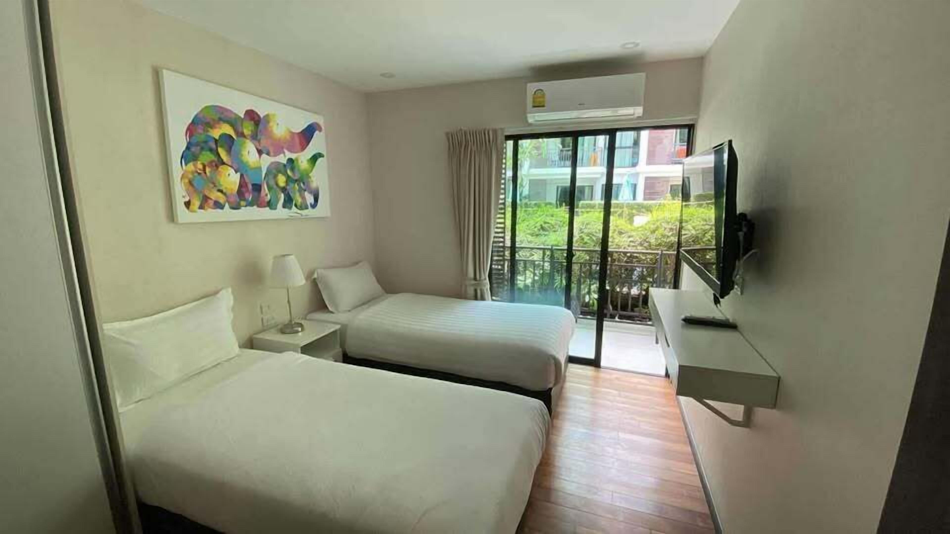 Een hotelkamer met twee bedden, een schilderij, een televisie en een balkon met uitzicht.