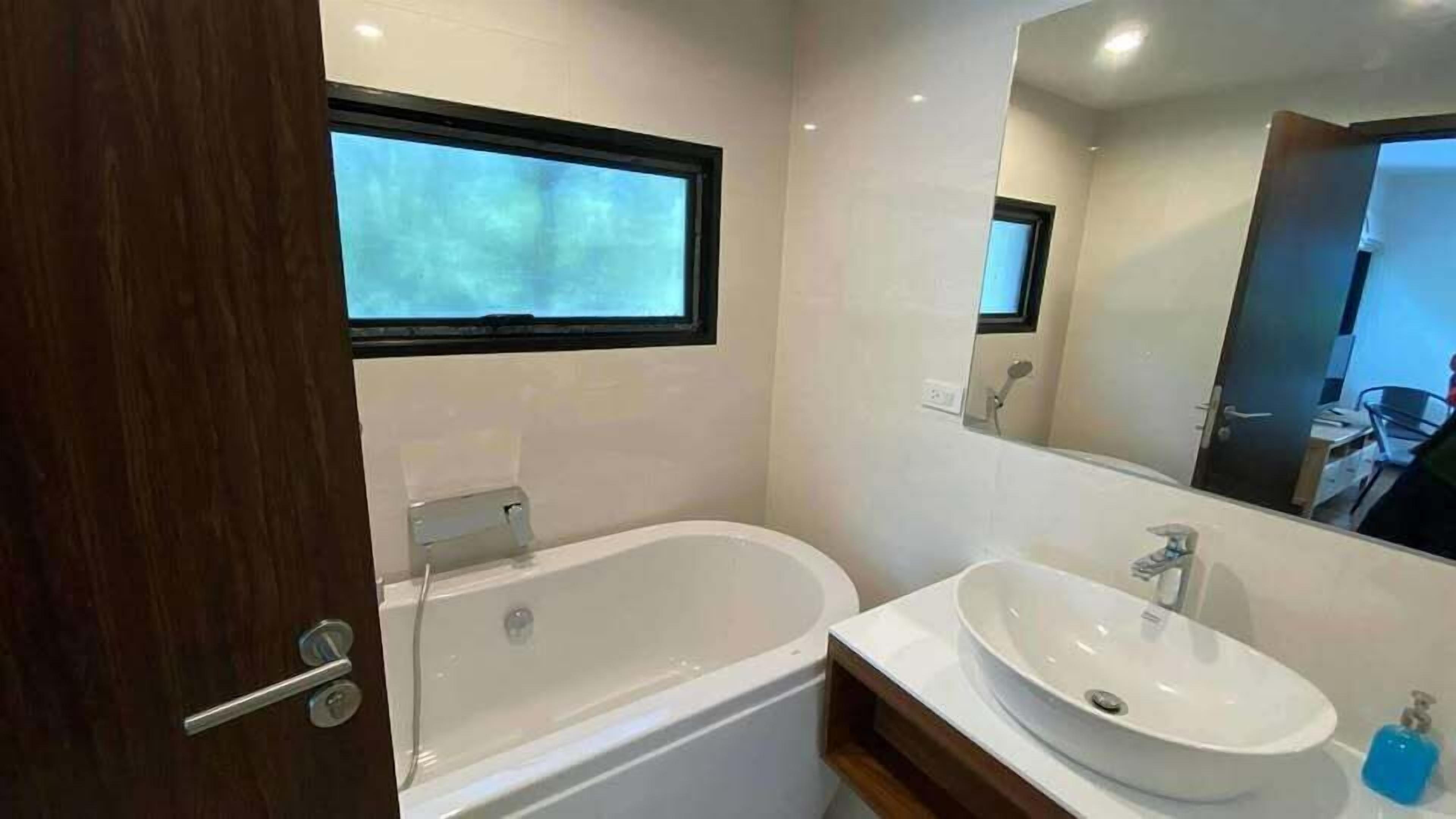 A modern bathroom with a bathtub, a sink, and a window.