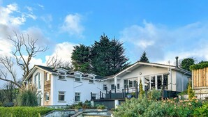 Ein modernes Haus mit großem Garten, Teich und einem hohen Baum.