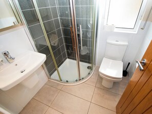 Ein modernes Badezimmer mit einer Duschkabine, einem weißen Waschbecken und einer Toilette.
