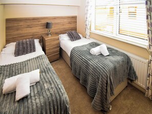 A hotel room with two beds, a nightstand, a lamp, and a window with blinds. - Attractive two bedroom, two bathroom lodge, with hot tub. (Water Yeat, Cumbria)