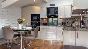 A modern kitchen with white cabinets, a dining area with a table and chairs, and a skylight above. - 2 bedroom accommodation in Buckden, near Skipton (Buckden, near Skipton)