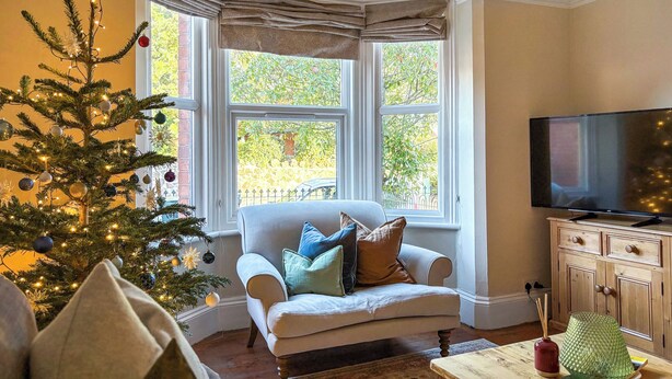 Un salon chaleureux avec un sapin de Noël, un canapé confortable, un téléviseur et un meuble en bois.
