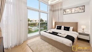 Una habitación de hotel moderna con una cama grande, una araña de cristal, vistas a la ciudad y un balcón.