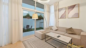 Una sala moderna con sofá, mesa de centro y un ventanal con cortinas.
