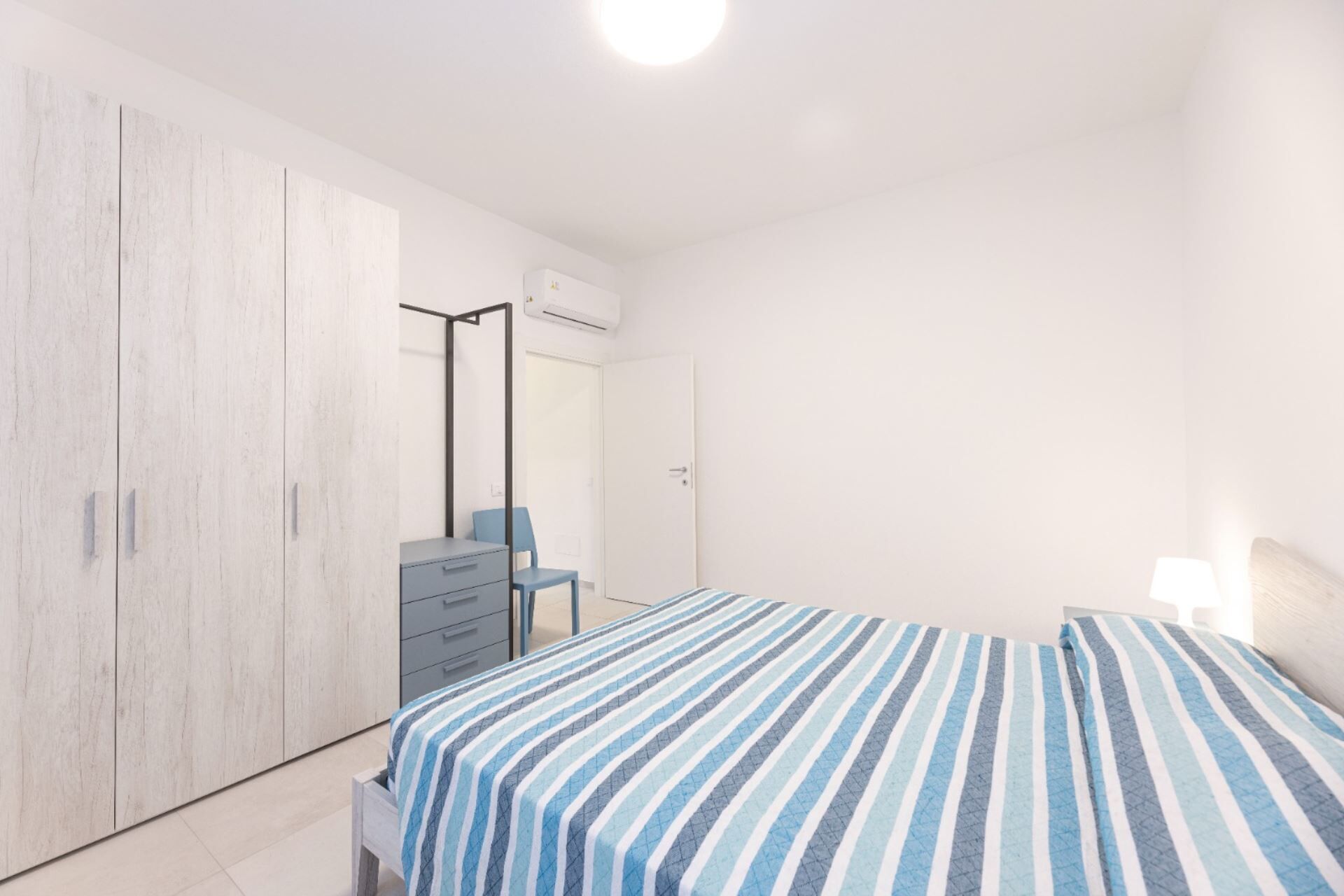 Ein Schlafzimmer mit Bett, Kommode, Spiegel und Kleiderschrank.