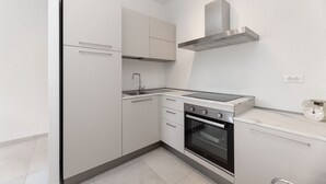 Een moderne keuken met witte kasten, een gasfornuis, een oven en een rvs-afzuigkap.