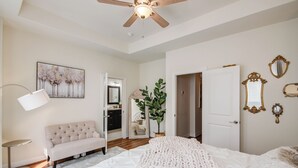 A bedroom with a bed, a sofa, a ceiling fan, a floor lamp, and a mirror. - Famous Houston Heights Home & Game Room (Houston)