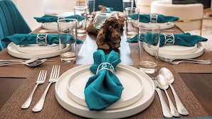 A dining table set with white plates, teal napkins, and silverware. - Famous Houston Heights Home & Game Room (Houston)