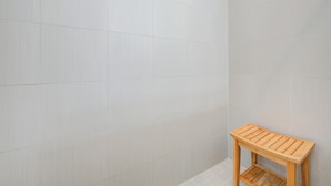 A corner of a room with light-colored tiled walls and a wooden bench. - Famous Houston Heights Home & Game Room (Houston)