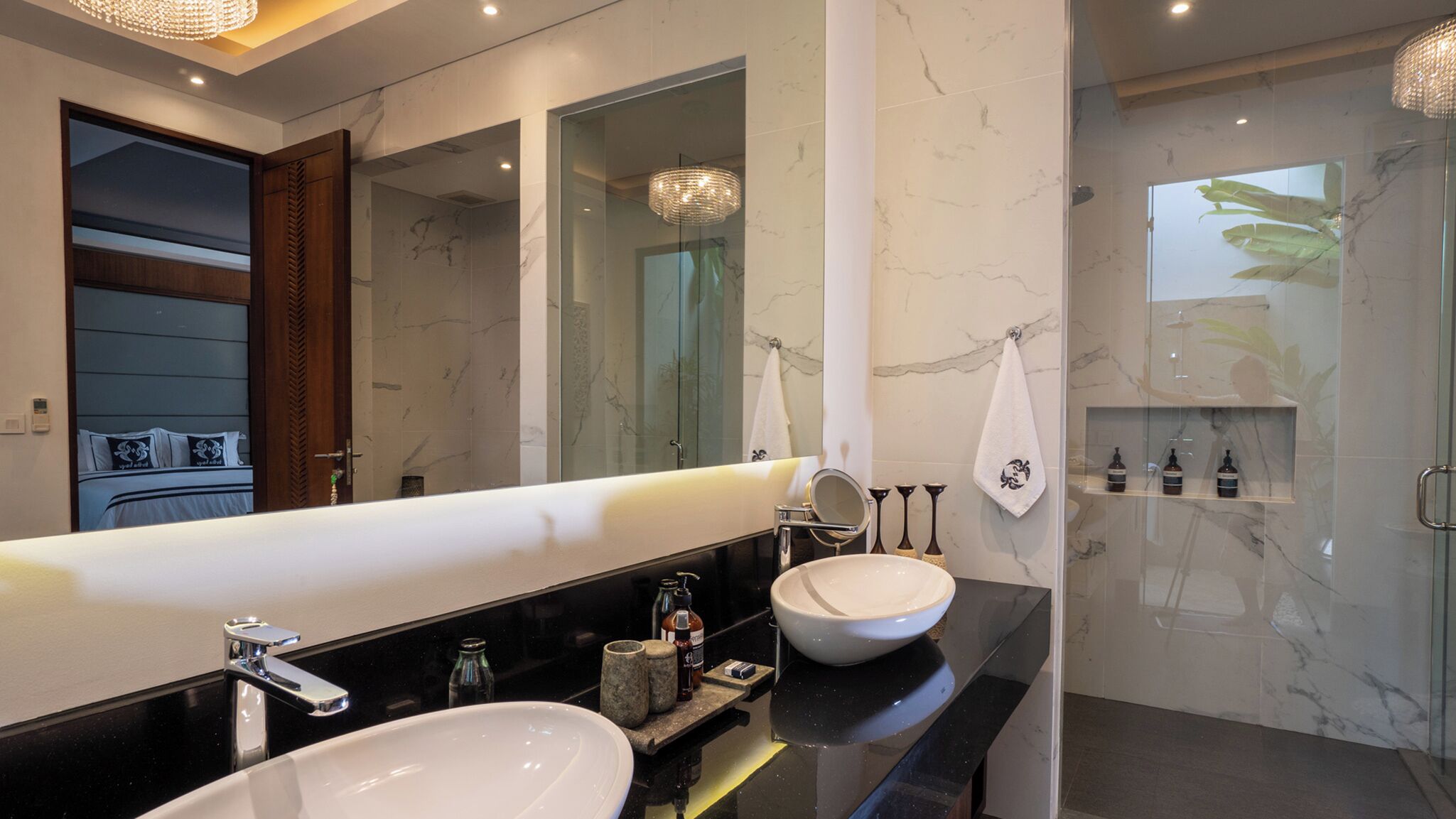 A modern bathroom with a large mirror, two sinks, and a shower area.