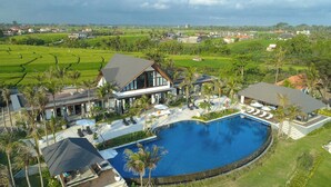 Un grande resort con piscina centrale, diverse ville per gli ospiti e un ambiente circostante ricco di verde.