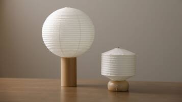 Two paper lanterns on a wooden table against a plain background.