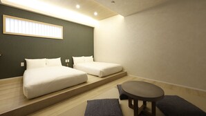 Et moderne hotelværelse med to senge, et lille bord og en tatamimåtte.