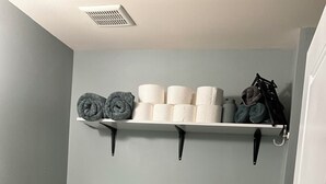 Et badeværelse med toilet, håndvask, bøjlestang til håndklæder og toiletpapir.