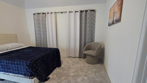 A bedroom with a bed, a chair, a painting, and a window with curtains. -  2 private rooms upstairs in a 4-bedroom house with AC. its not for entire house (Fort Worth)
