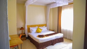 A bedroom with a bed, bedside table, lamp, and curtains. - Acacia Boutique Hotel (Mbarara)
