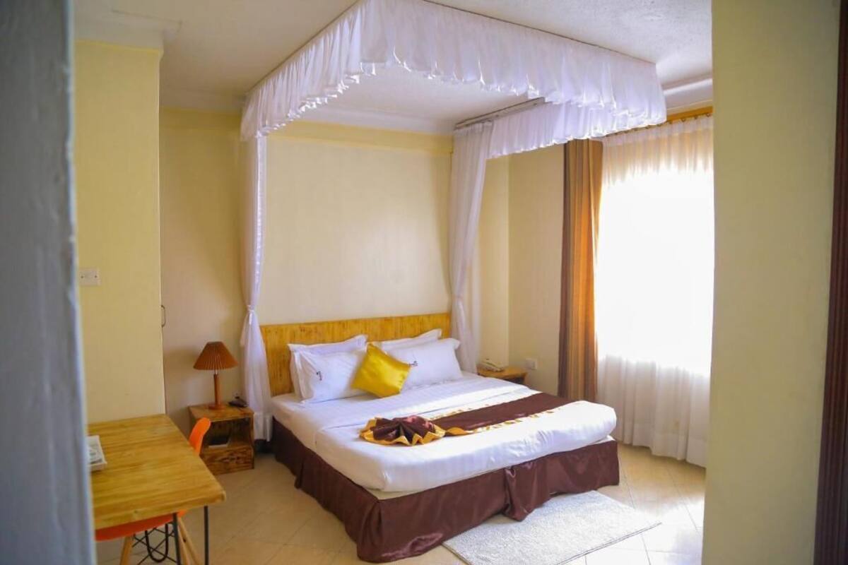 A bedroom with a bed, bedside table, lamp, and curtains.