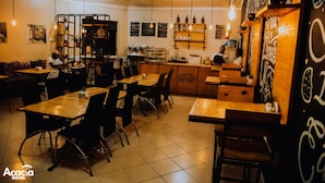 A cozy restaurant with wooden tables and chairs, a bar area, and various wall decorations. - Acacia Boutique Hotel (Mbarara)