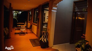 A reception area with a coffee shop sign, a reception desk, chairs, and a potted plant. - Acacia Boutique Hotel (Mbarara)