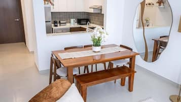 Een eetgedeelte met een houten tafel, stoelen, een bankje en een potplant.