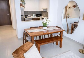 Un comedor con mesa de madera, sillas, un banco y una planta en maceta.