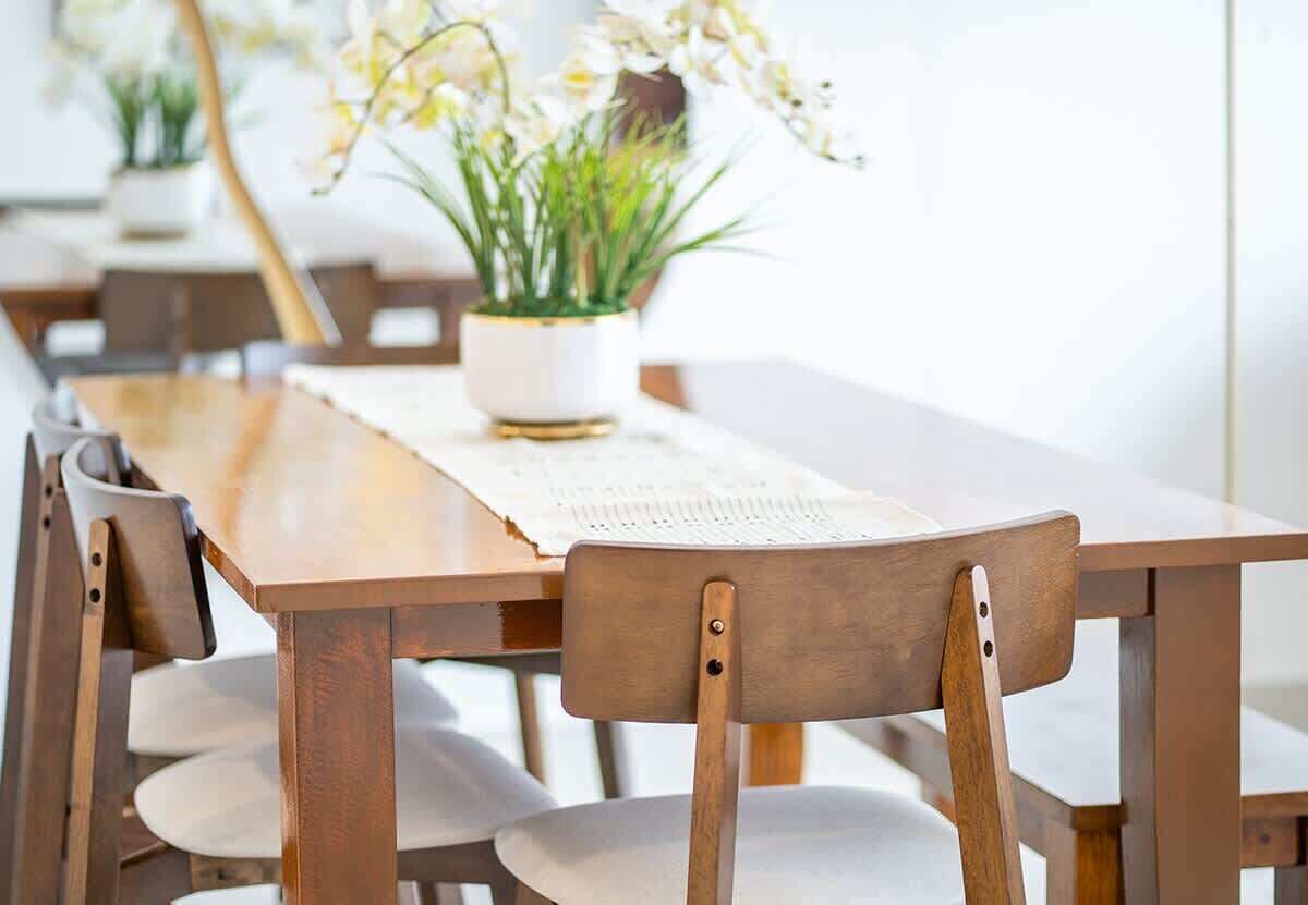 A wooden dining table with chairs, a placemat, and a potted plant with white flowers.