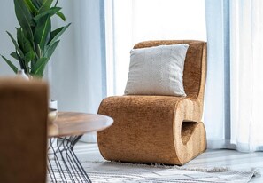 A room with a woven chair, a white cushion, a plant, and a round table. - Lagoon View Apartment w/ Pool, Beach & Gym Access (Ajmal Makan)