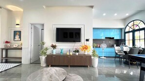 Un soggiorno moderno con una grande TV, un'area pranzo e una cucina sullo sfondo.