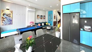 Un soggiorno moderno con tavolo da biliardo, area salotto e cucina con mobili blu.