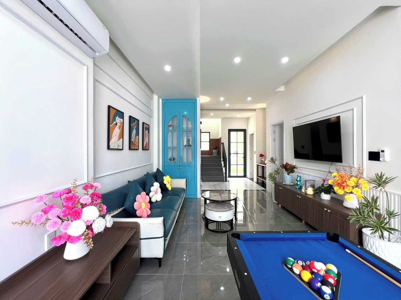 A modern living room with a sofa, a pool table, and a TV.