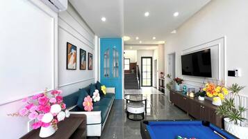 A modern living room with a sofa, a pool table, and a TV.