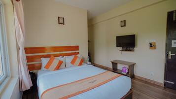 Una habitación de hotel con una cama, televisión, una mesita y una puerta.