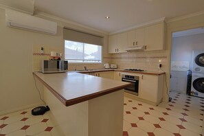 Eine kleine Küche mit Mikrowelle, Toaster, Backofen und Waschmaschine.