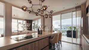 Una cocina moderna con una isla central, taburetes de bar y una lámpara esférica original.