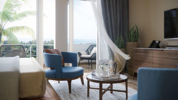 Ein modernes Wohnzimmer mit Meerblick, ein blaues Sofa, ein Couchtisch und ein Fernseher an der Wand.