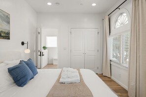 A bedroom with a bed, pillows, a bedside table, a lamp, a door, and a window with blinds. - Bright and Modern 3BR/2.5BA Home Near Downtown SJ, Airport, Stadiums & Tech Hubs (San Jose)