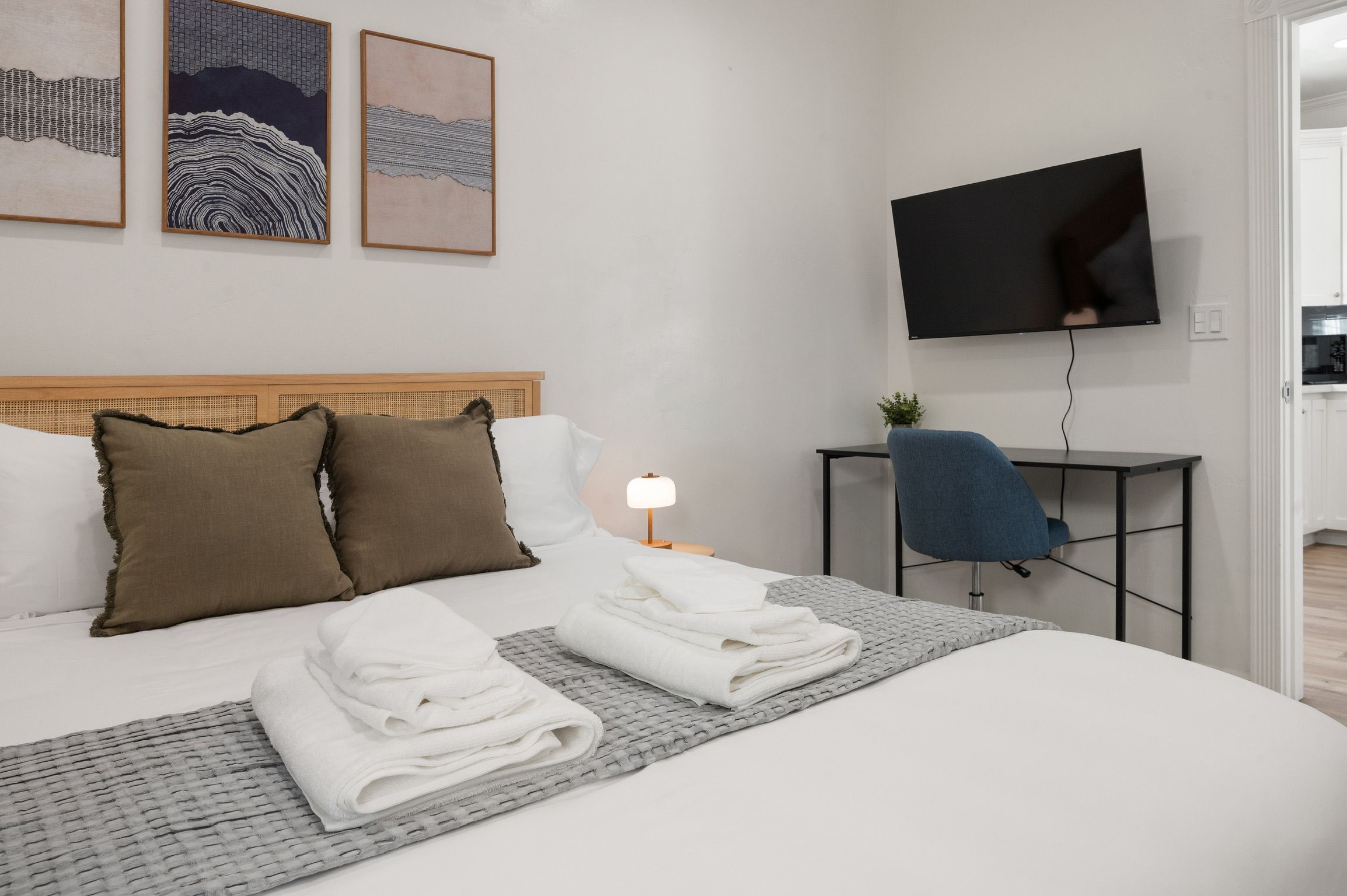 Une chambre d’hôtel comprenant un lit, un bureau avec une chaise, un téléviseur à écran plat et des œuvres d’art accrochées au mur.
