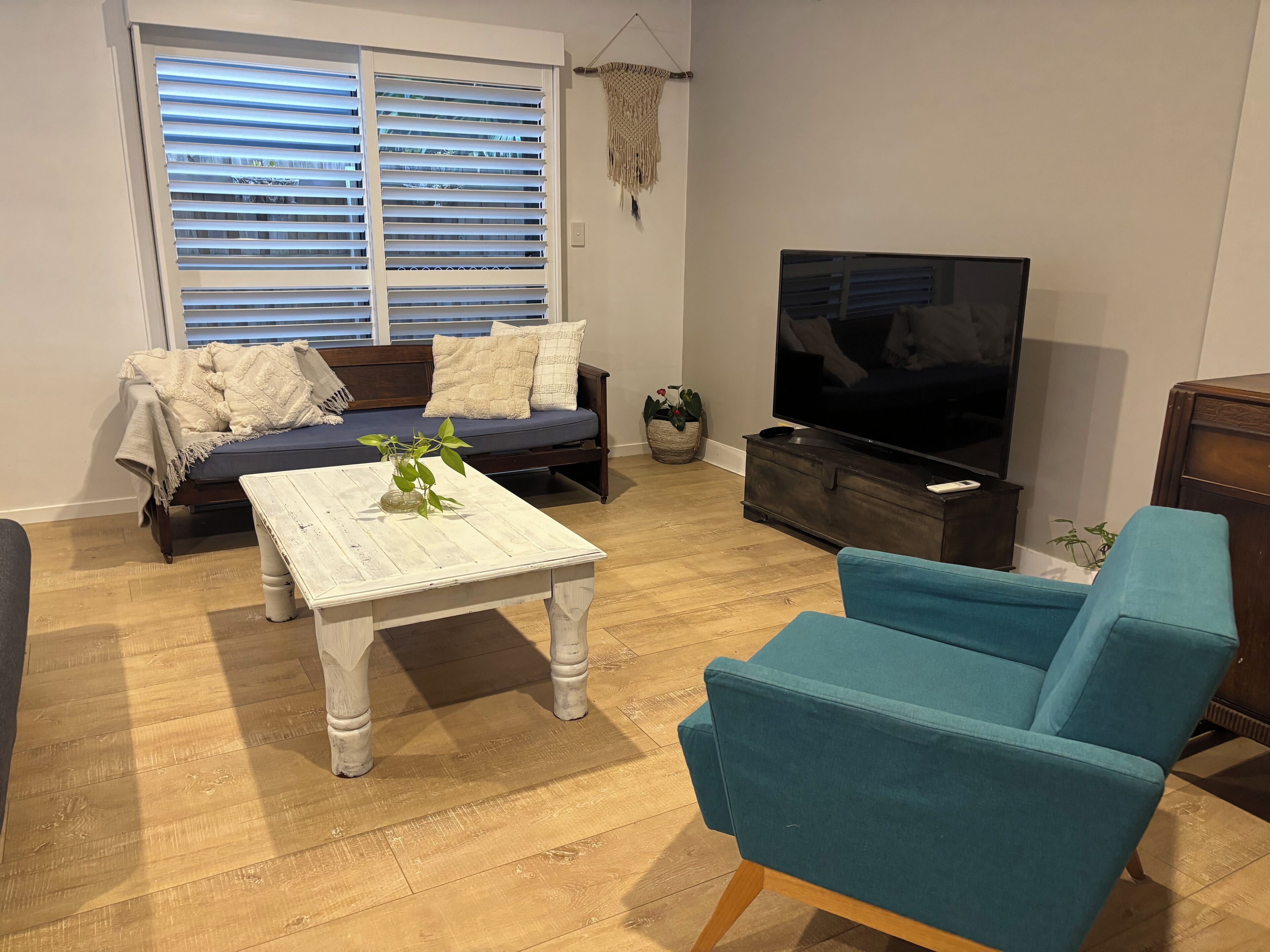 Un salon avec un canapé, une table basse, un téléviseur et un fauteuil bleu.
