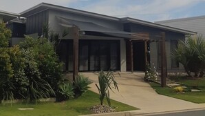 Een modern herenhuis met twee verdiepingen, een overdekte veranda, een garage en een verzorgd gazon met diverse beplanting.