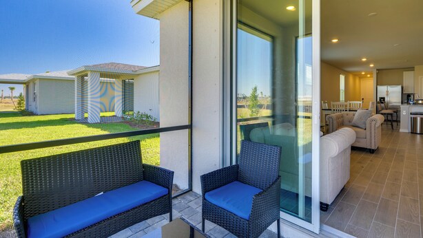 Ein Balkon mit Korbmöbeln und Blick auf ein Haus und Garten.