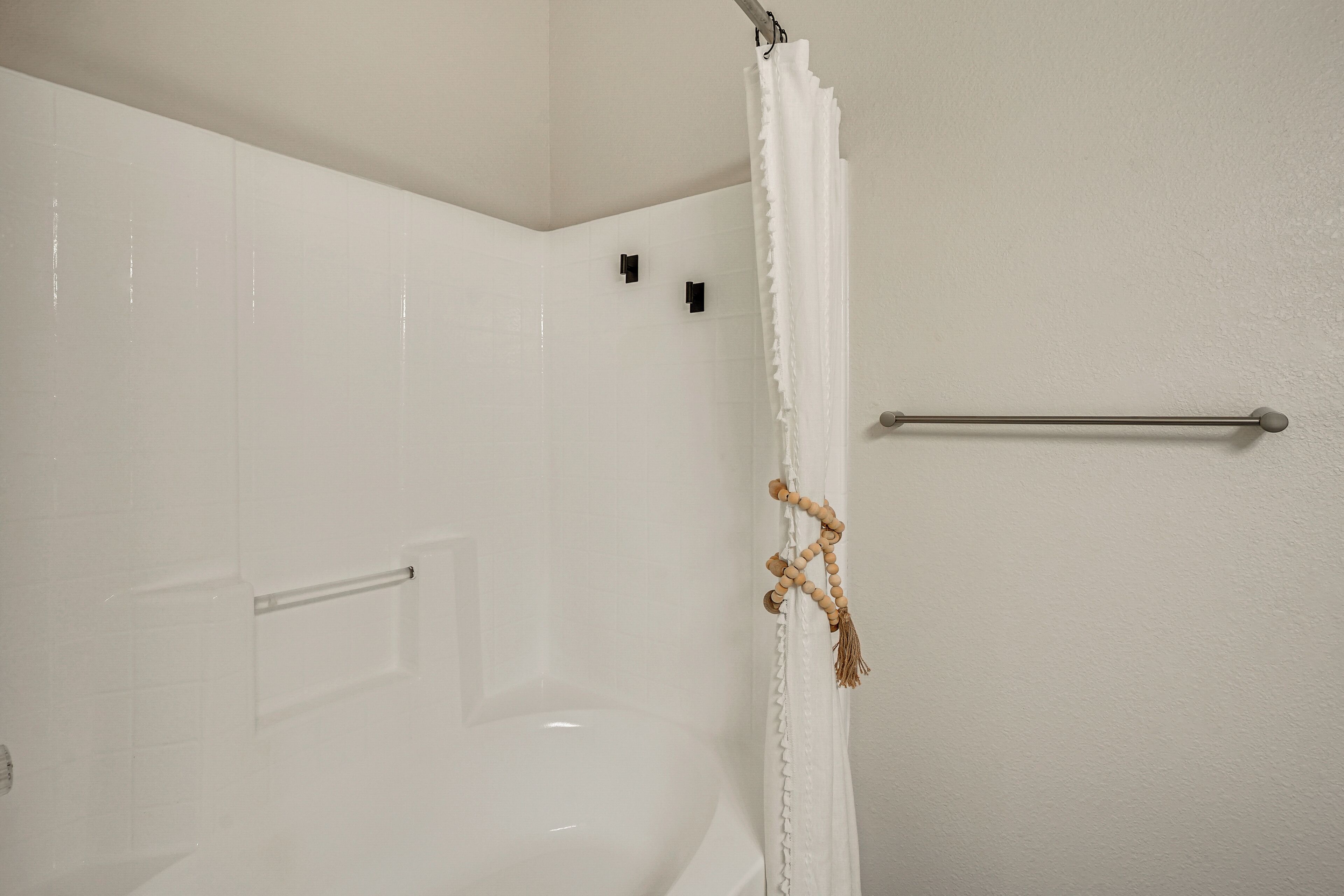 A bathroom with a white bathtub, a shower curtain, and a towel rack.